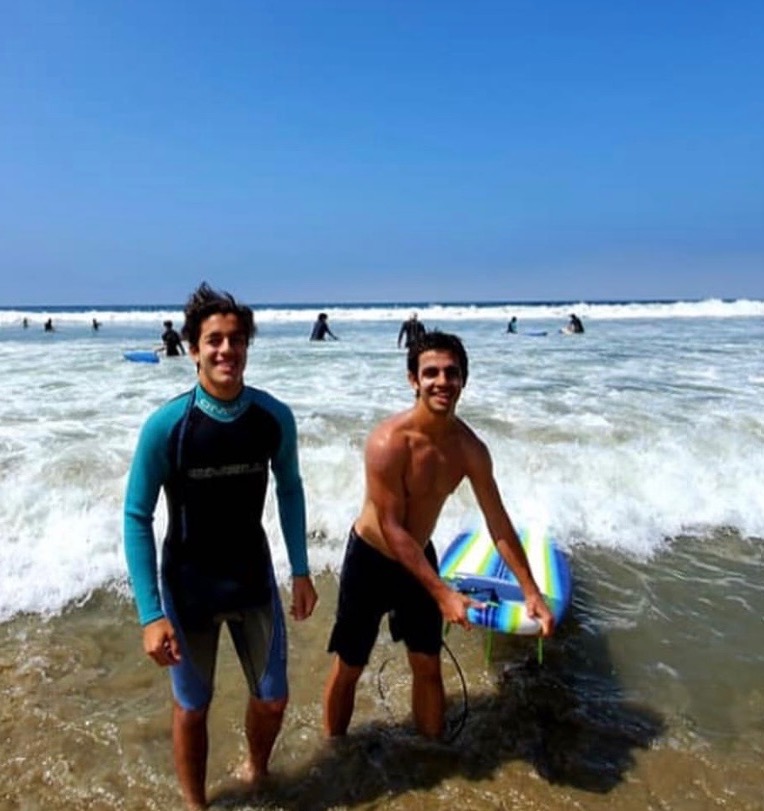 Ezra surfing with a student